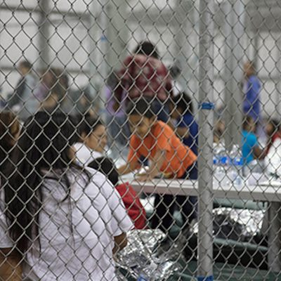 Women and children sitting in cages at a detention center