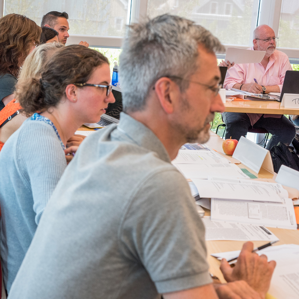 Row of people sitting at a table watching a presentation