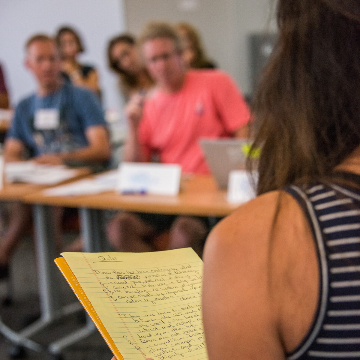 Woman holding a yellow notepad titled 'Quotes'