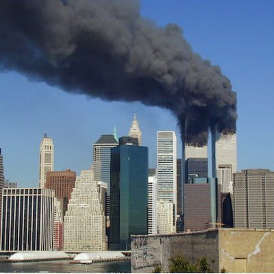 The Twin Towers with smoke billowing from into the blue sky following terrorist attacks on 9/11