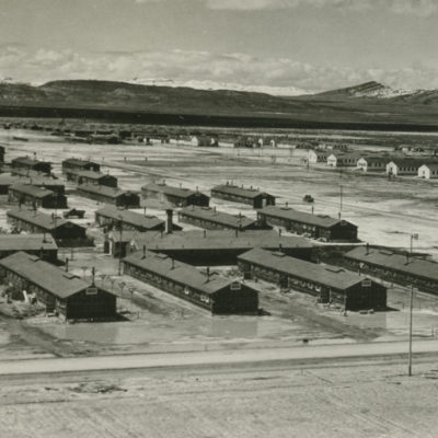 Several rows of long, one-story buildings on a flat desert plain.
