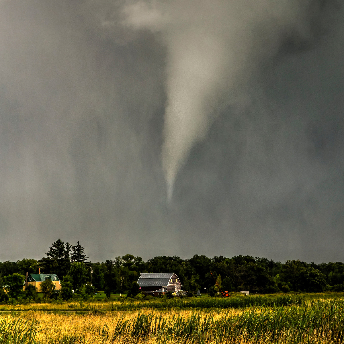 A tornado above a house on the edge of a field