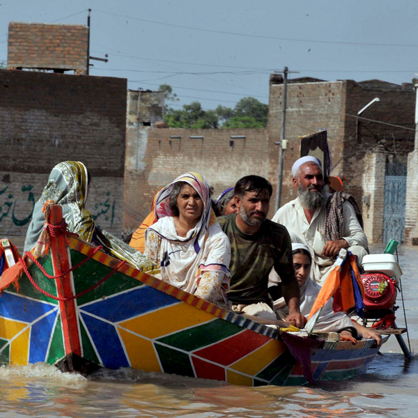 A family sitting in a wooden boat in a flood