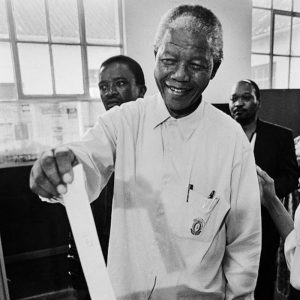 Nelson Mandela putting a ballot in a ballot box.