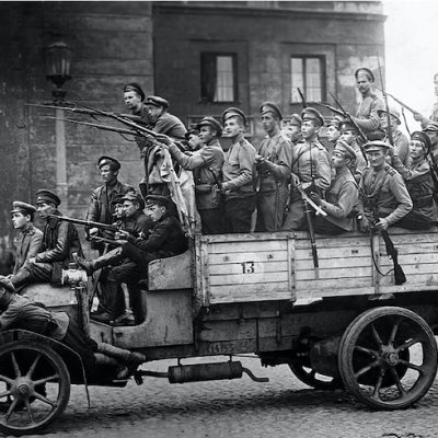 Black and white photo of an old Russian army truck loaded with soldiers wielding their guns