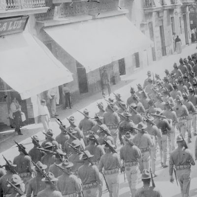 Black and white photo of lines of US troops marching down a city street