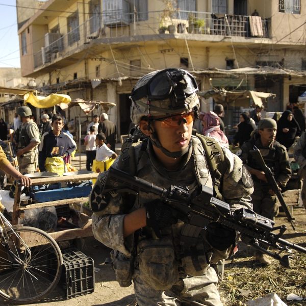 U.S. troops patrolling in Baqubah, Iraq, during the U.S. military occupation, 2007. Soldiers carrying automatic weapons walk through a crowded market place.