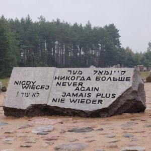 Holocaust memorial at Treblinka with a large rock inscribed with the worlds "Never Again" in multiple languages