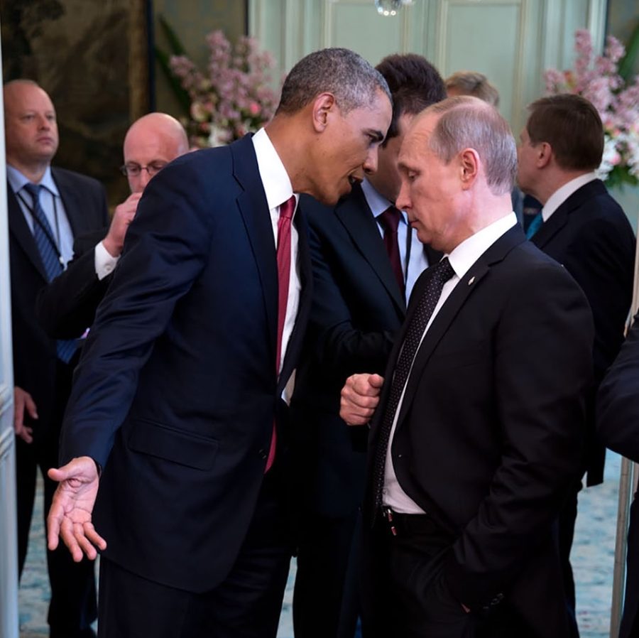President Obama leans in to say something to Vladimir Putin as other men stand in the background.
