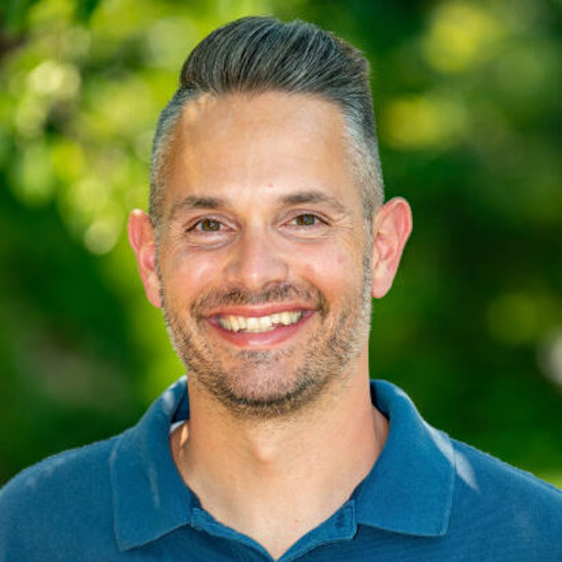 Mario Fitzpatrick headshot with a blurred green background