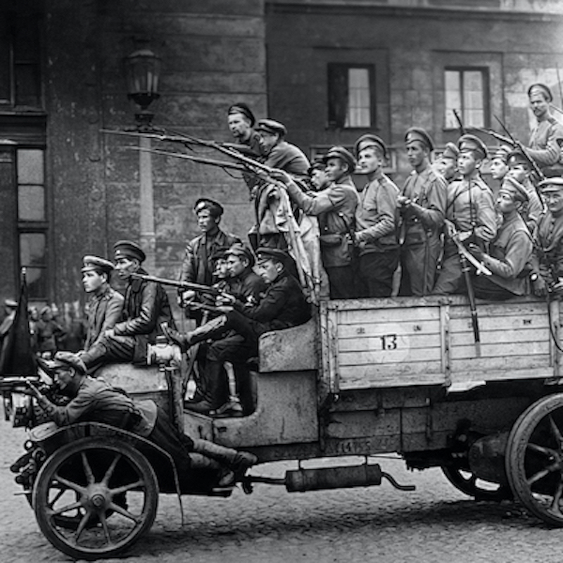 Black and white photo of an old Russian army truck loaded with soldiers wielding their guns